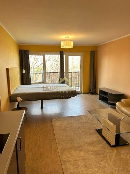 A spacious room in a 3-room apartment with a wood-patterned floor and large windows.