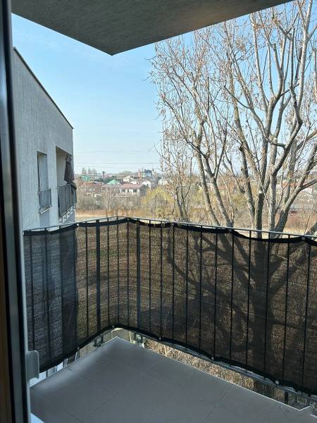 A balcony with a view of trees and buildings, located in a 3-room apartment on Bosákova Street in Bratislava - Petržalka.