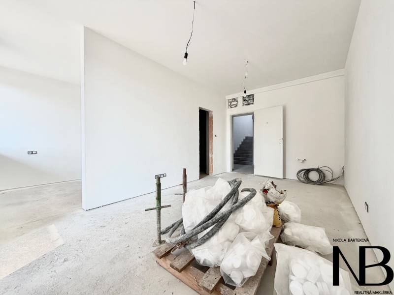 A one-room apartment with white walls and a concrete floor.