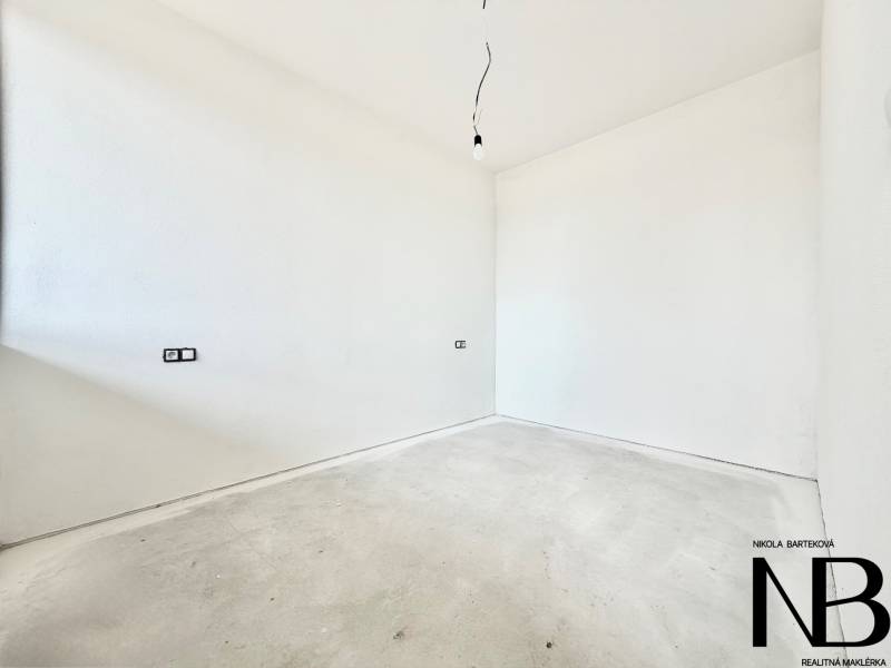 An empty room with white walls and a floor with wood decor in a studio apartment.