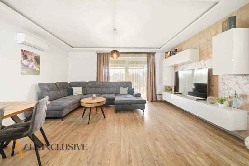 Living room of a family house with a comfortable sofa and a wooden-patterned floor.