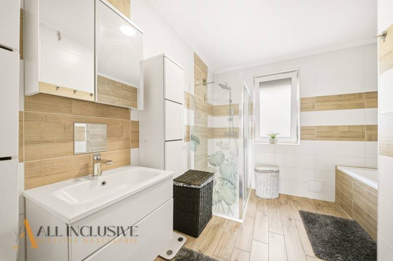 A bathroom in a family house with a wooden decor floor and a shower corner.
