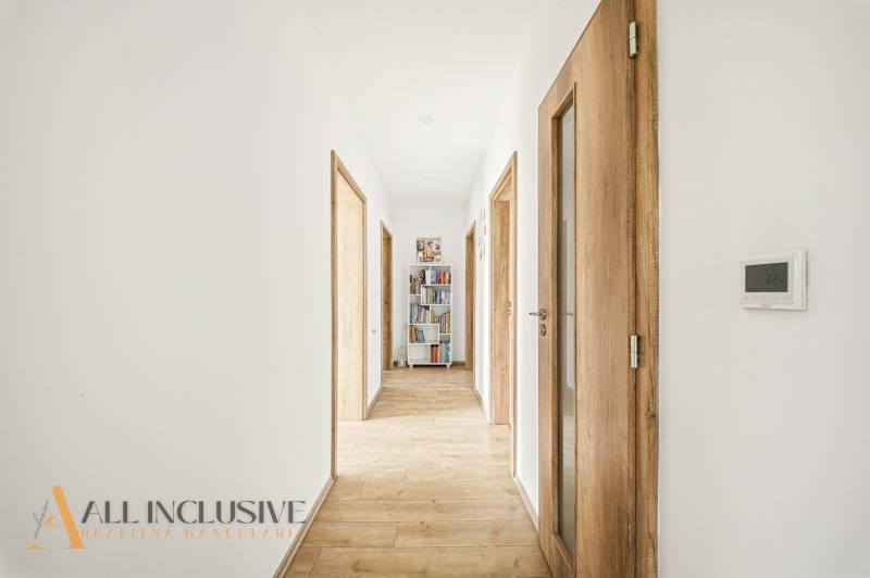 A narrow hallway with a wooden decor floor and a bookshelf in a family house.