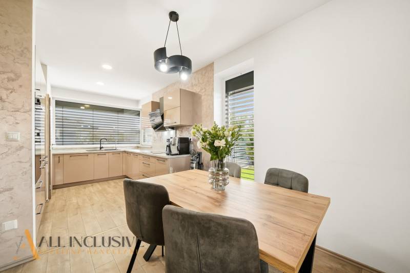 A kitchen in a family house, with a dining table, a wooden-patterned floor, and floral decorations.