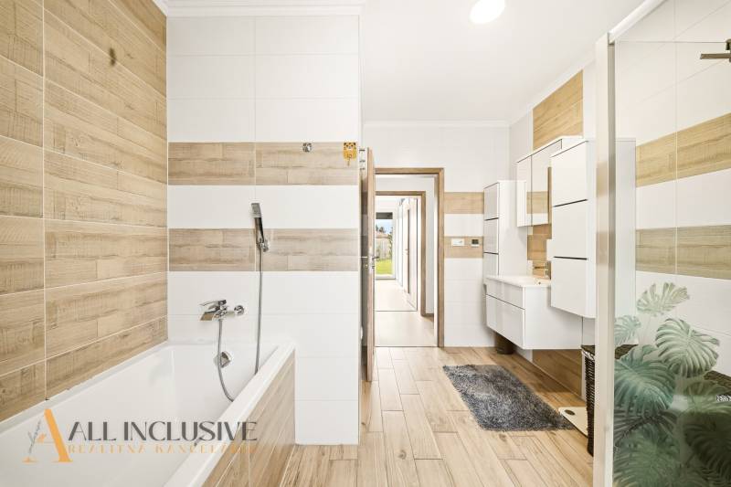 A bathroom in a family house with a wooden decor floor and a bathtub.