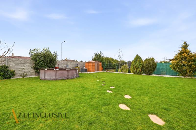 A garden of a family house in Dunajská Streda with a lawn, a swimming pool, and a garden house.