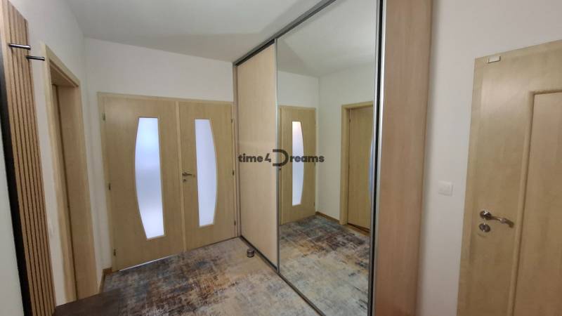 A hallway in a 2-room apartment with a large mirror and light-colored furniture.