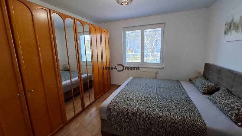 Bedroom with a double bed, mirrored wardrobe, and wooden decor flooring in a two-room apartment.