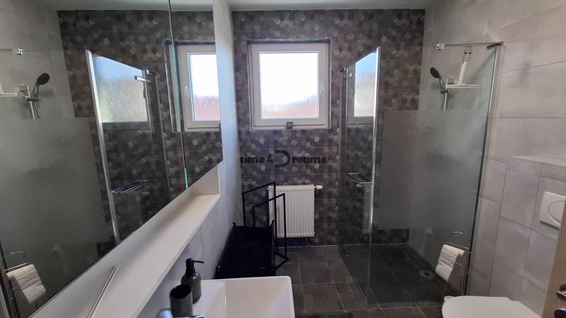 Modern bathroom in a 2-room apartment with a glass shower enclosure and decorative tiles.
