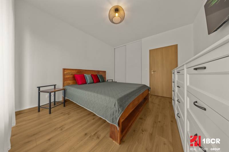 Bedroom in a 2-room apartment, bed, dresser, floor with wooden decor.