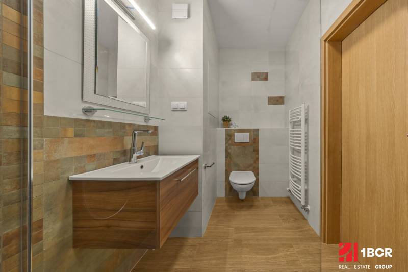 Bathroom in a 2-room apartment with a wooden decor floor and a modern sink.