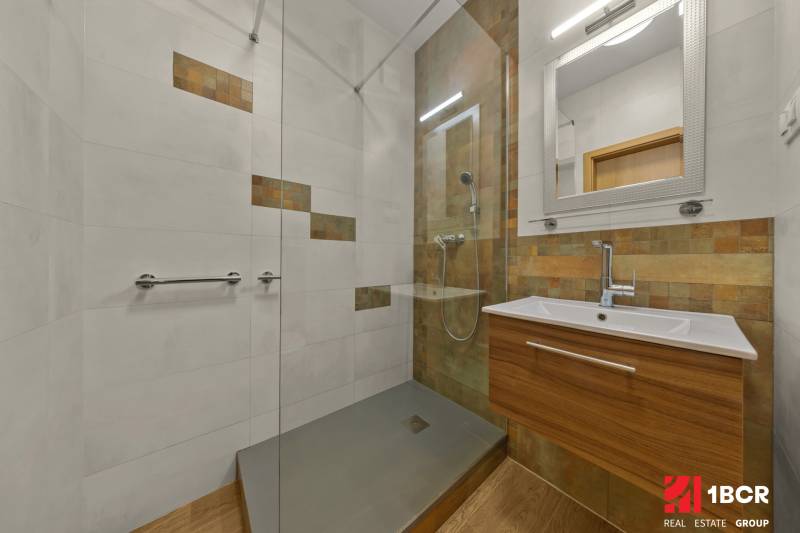 Bathroom with tiles and a wooden decor floor in a 2-room apartment.
