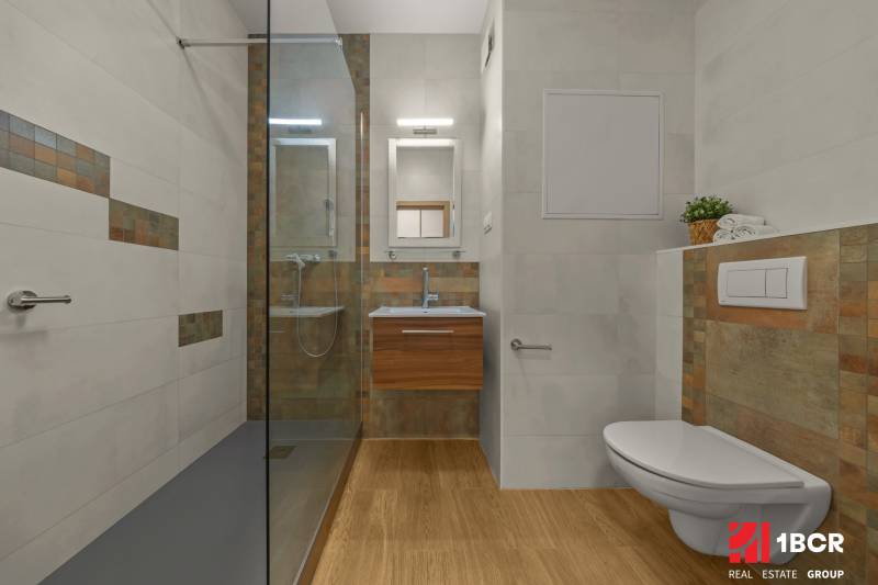 Bathroom in a 2-room apartment with wood-patterned flooring, a shower, and a toilet.