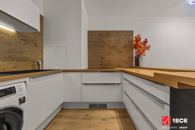 A kitchen in a 2-room apartment with a wooden decor floor and a decorative vase.