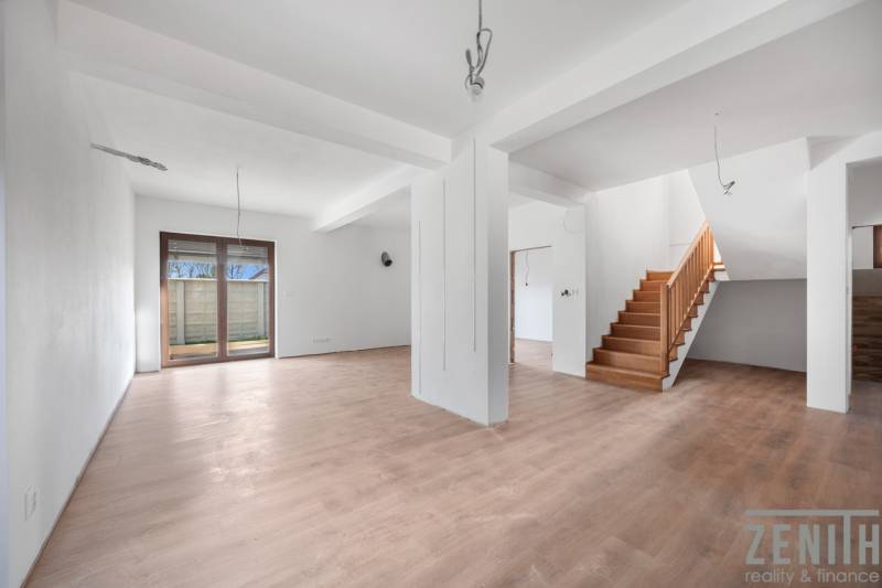 Interior of a family house with a spacious living room, staircase, and wooden decor flooring.