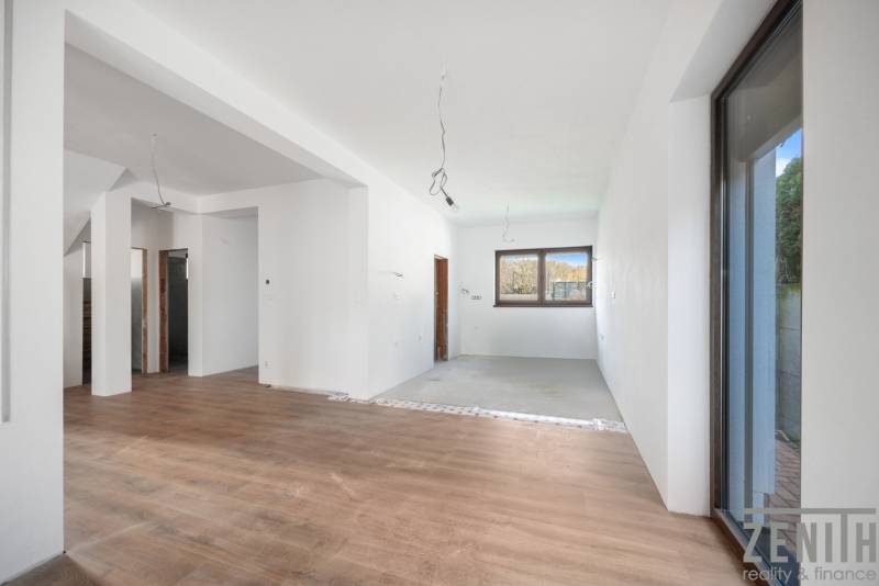 Interior of a family house with a window, white walls, and a floor with a wood decor.