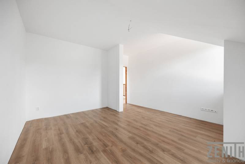 A spacious room with light walls and a floor with a wooden decor in a family house.