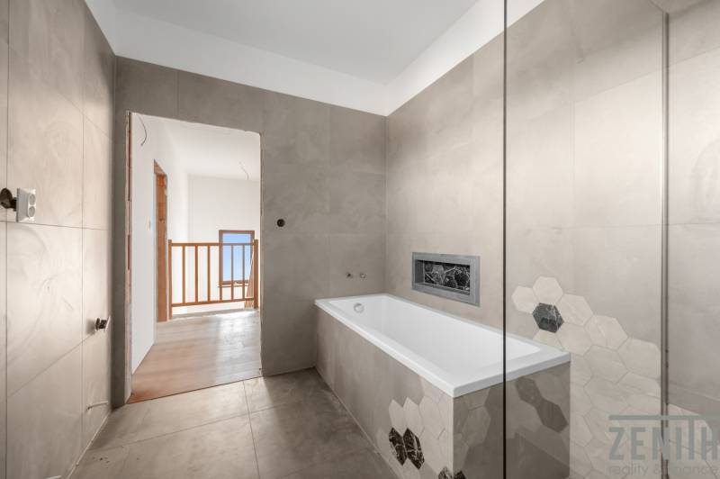 A bathroom with a bathtub and hexagonal tiles in a family house.