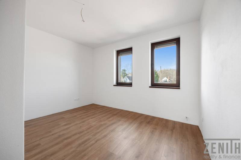 A room with two windows and a floor with a wooden decor in a family house.