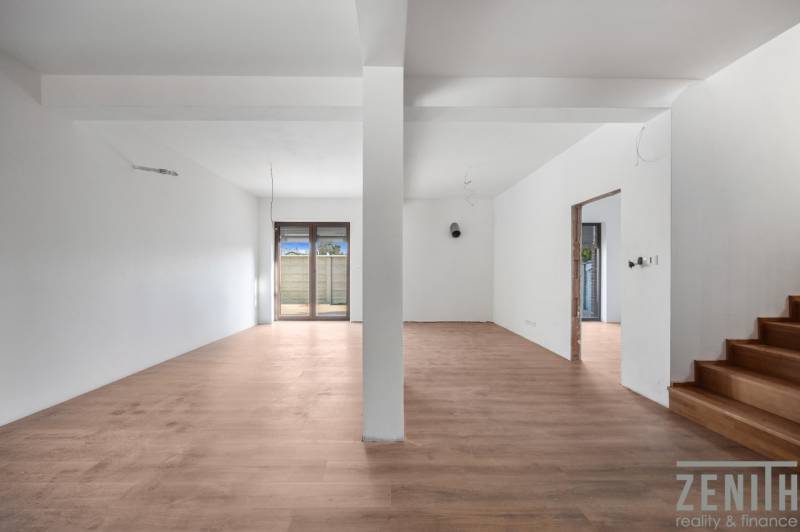 A spacious room in a family house with a wooden decor floor and glass doors.