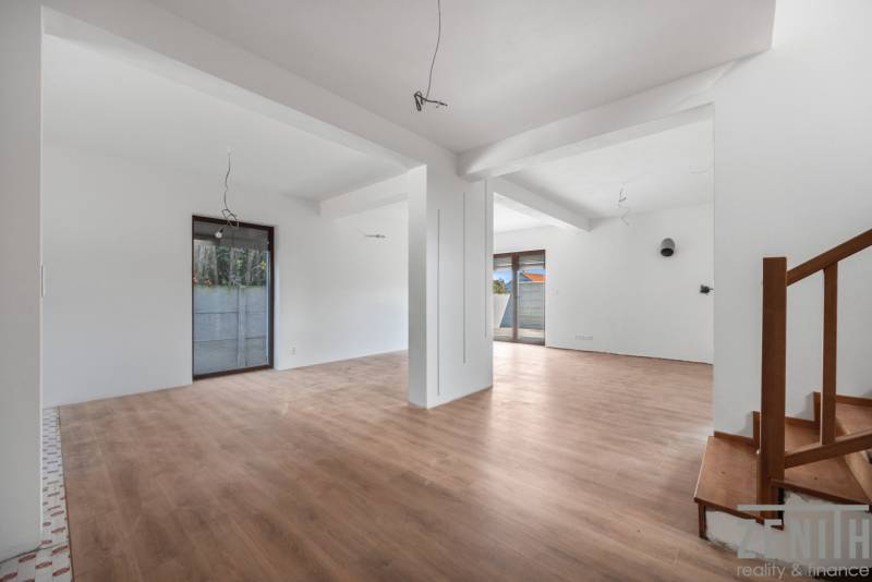 Spacious interior of a family house with a wooden decor floor and a staircase.