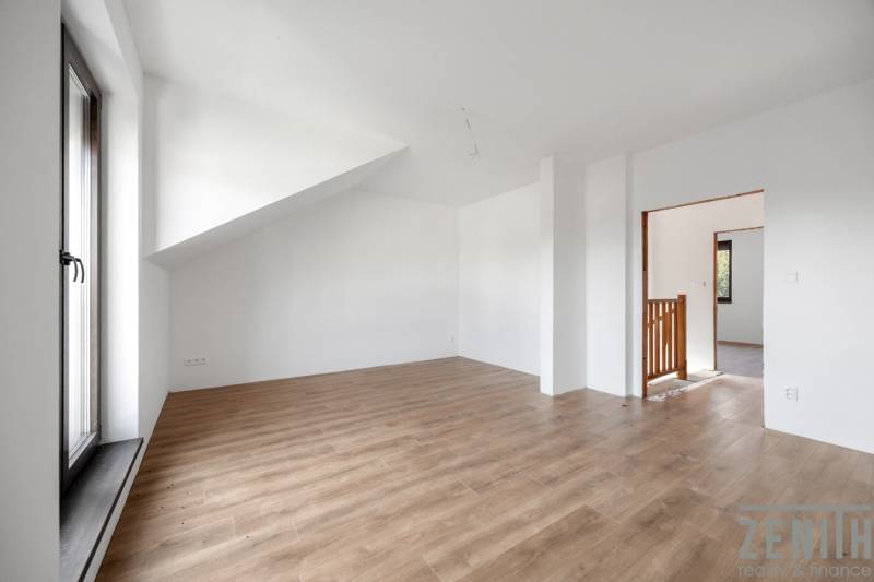A bright room in a family house with a wooden decor floor and a sloped ceiling.