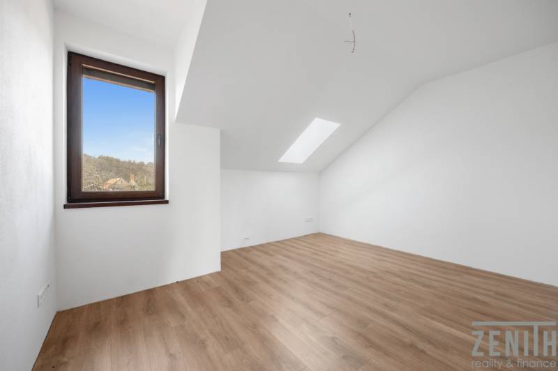 Attic room with a window and wooden decor flooring in a family house.