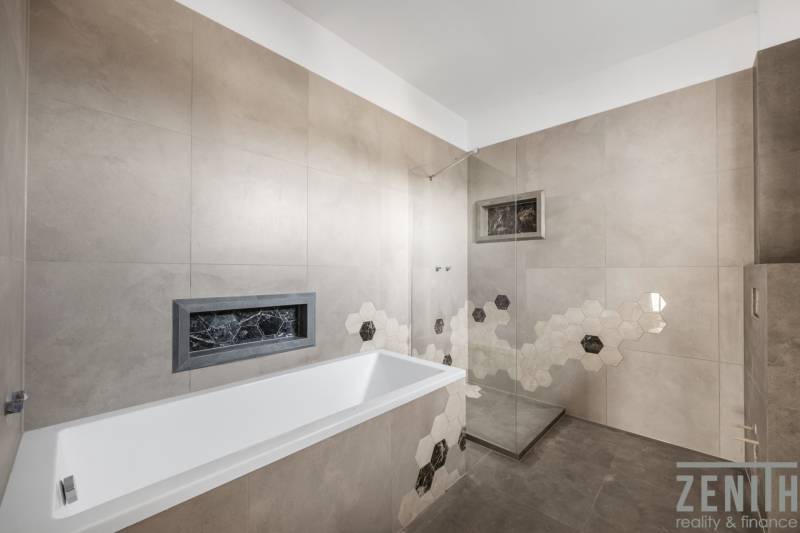 A bathroom in a family house with a bathtub and modern hexagonal tiles.