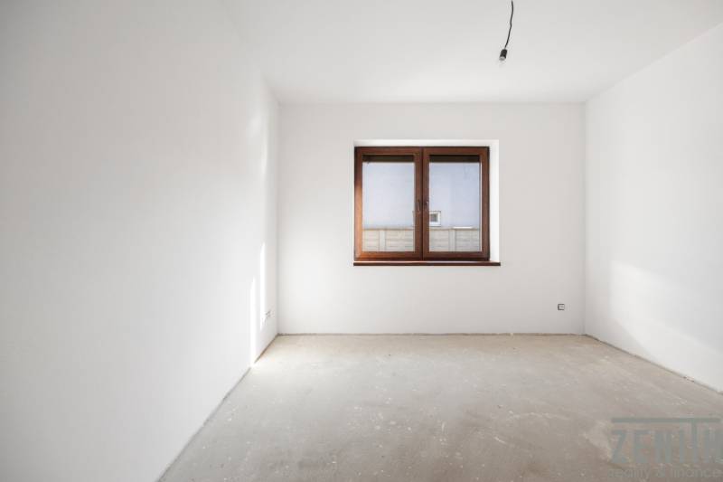 The room in a family house with white walls and a large window.