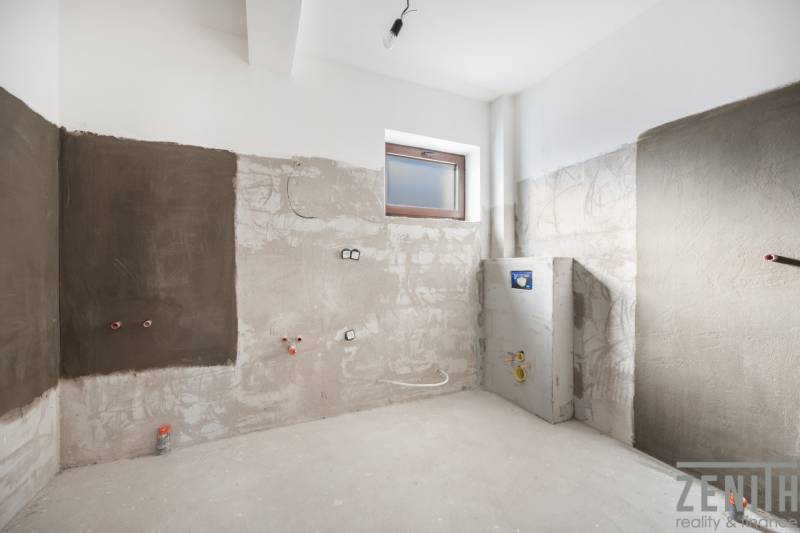 An unfinished room in a family house, ready for renovation, with a window and rough walls.