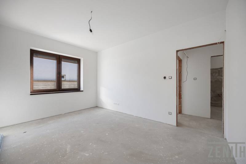 An unfurnished room with a window and a concrete floor in a family house.