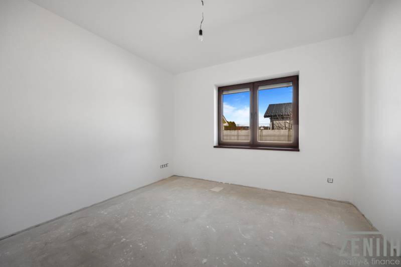 Corner room in a family house with a window, white walls, and spacious area.