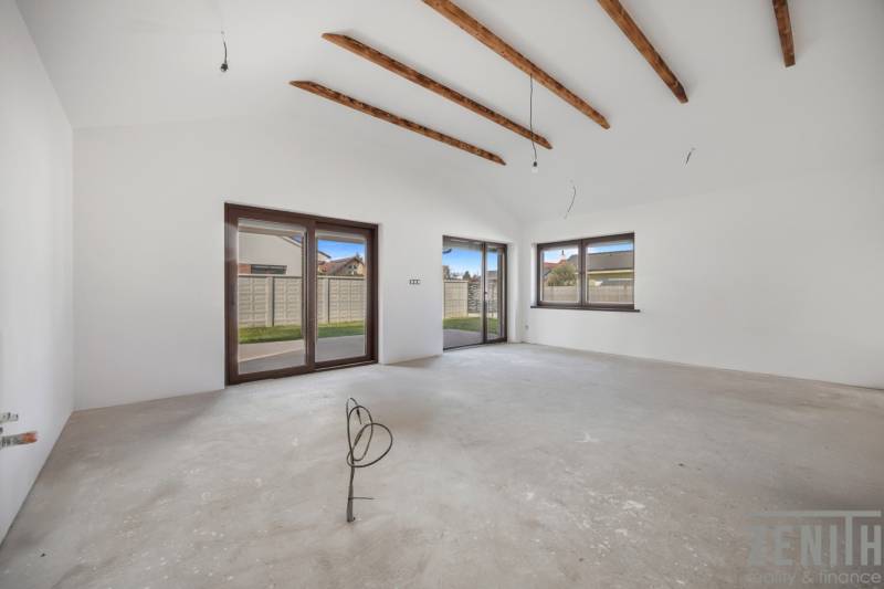 The interior of a family house with white walls and wooden beams on the ceiling.