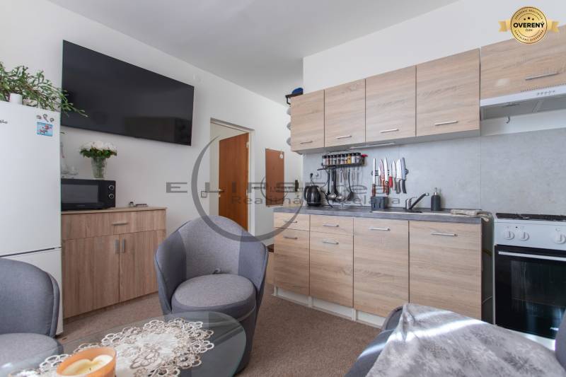 A kitchen in a studio apartment with wooden decor and a dining area.