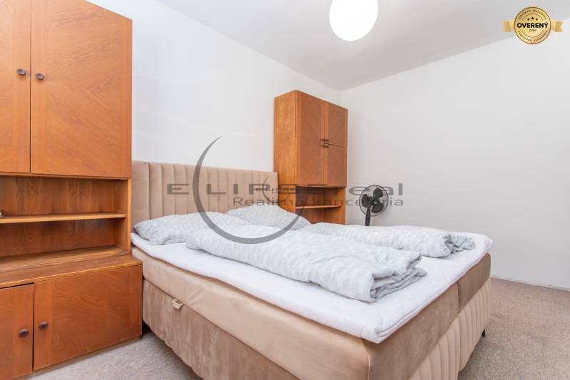 Upholstered headboard bed and wooden cabinets in a studio apartment.
