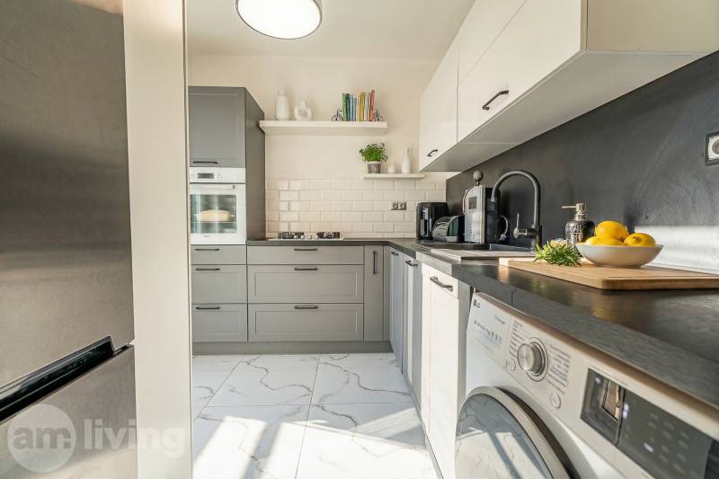 Kitchen in a 2-room apartment, gray cabinets, stone countertop, appliances.