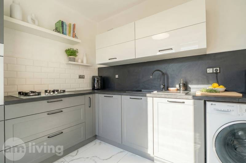 A kitchen in a 2-room apartment with modern equipment and light tiles.