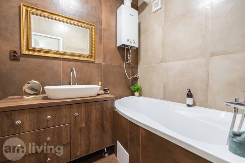 Bathroom with a bathtub and a sink in a 2-room apartment, floor with wooden decor.