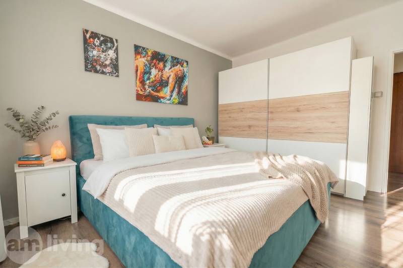 A bedroom with a bed, a wardrobe, and a wooden decor floor in a two-room apartment.