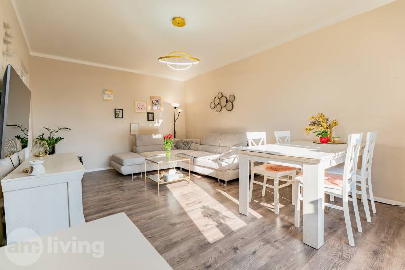 A bright living room with white furniture and a wood-patterned floor in a 2-room apartment.