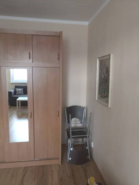 Wardrobe with a wooden decor floor in a studio apartment, cream walls, folding chairs.