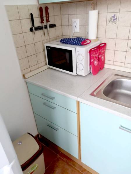 A kitchen in a studio apartment with a microwave and a sink on a spacious countertop.