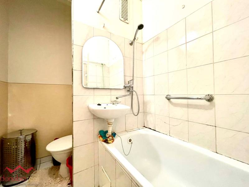 Bathroom in a studio apartment with a bathtub, sink, and toilet.