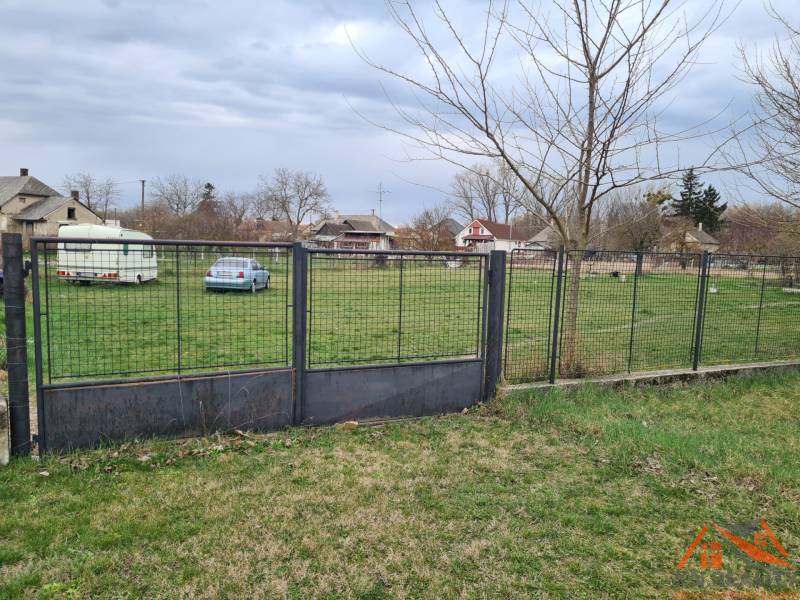 Plot surrounding a residential plot in Veľké Kosihy with a car and a trailer.