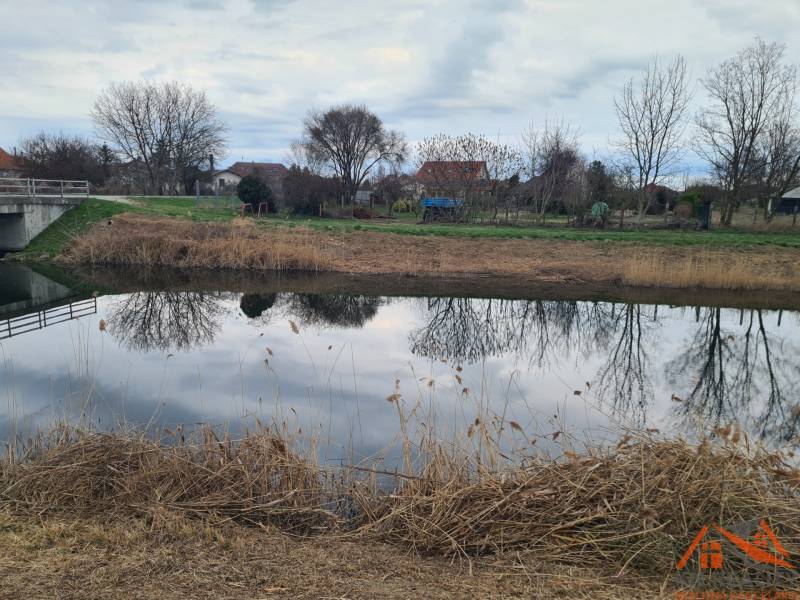 Water surface with reflection of trees near the bridge in Veľké Kosihy, land - residential.