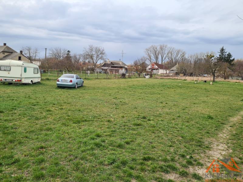 Lands - living in Veľké Kosihy with greenery, a car, and a trailer in the background.