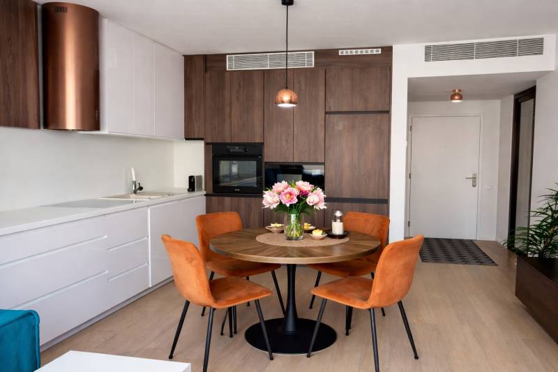 A kitchen in a 2-room apartment with a round table and chairs, flooring with a wooden decor.
