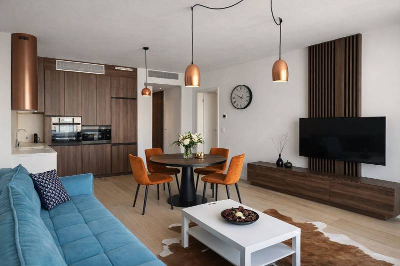 Living room with a sofa, dining table, and kitchen in a two-room apartment, floor with wood decor.
