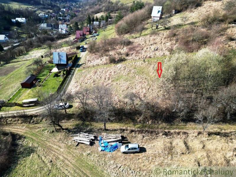 Residential plots in Vydrná with a view of the hilly landscape and houses.