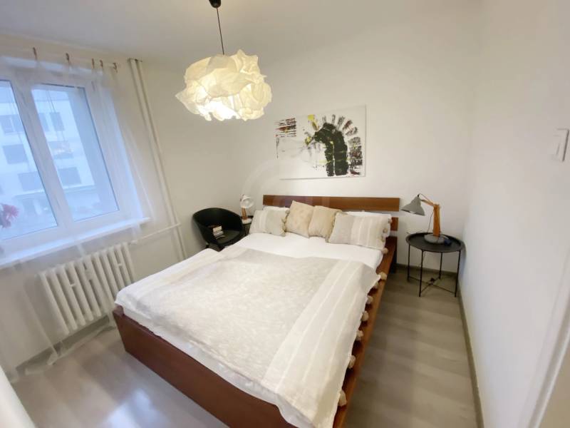 Bedroom in a 2-room apartment with a bed, armchair, and decorative lighting.